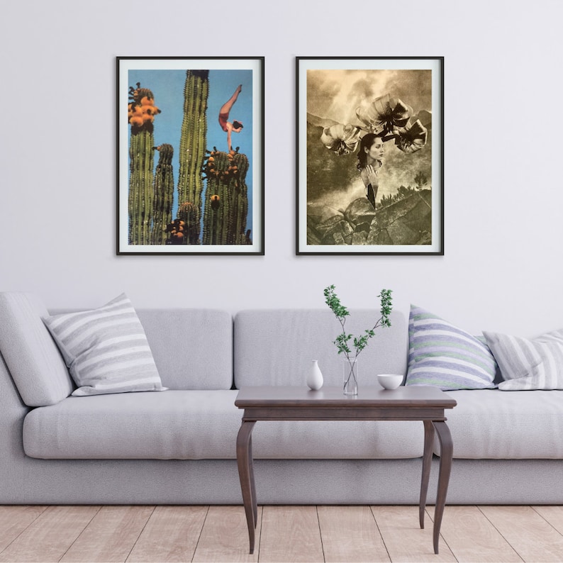 May include: Two framed art prints hanging on a white wall above a gray couch. The print on the left shows a woman doing a handstand on top of a tall cactus. The print on the right shows a woman with flowers on her head standing in a desert landscape.
