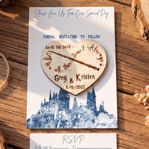 May include: A wedding invitation suite featuring a heart-shaped wooden save-the-date with the names "Greg & Kristen" and the date 1/18/2023. The invitation and RSVP card have a blue castle design. The text reads "Please Join Us For Our Special Day".