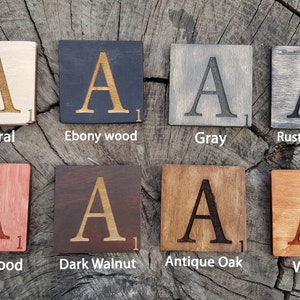 Pu&ograve; includere: Otto tessere di legno con la lettera 'A' e il numero '1' su di esse. Le tessere sono in diverse macchie di legno, tra cui naturale, legno di ebano, grigio, ebano rustico, legno di ciliegio, noce scuro, rovere antico e noce.