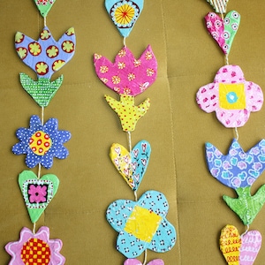 Peut inclure: Une guirlande en papier colorée avec des fleurs, des cœurs et des tulipes. La guirlande est faite de papier et est décorée de différents motifs et couleurs.
