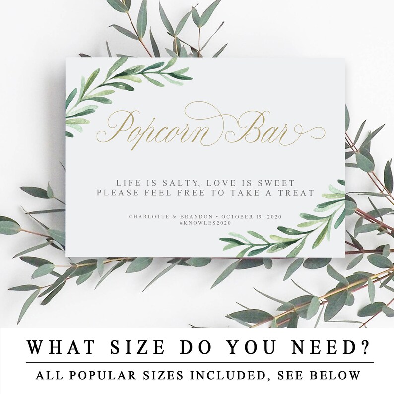 May include: A printable sign for a popcorn bar at a wedding or party. The sign is white with green watercolour leaves and gold calligraphy that says "Popcorn Bar". The text below reads "Life is salty, love is sweet. Please feel free to take a treat." The bottom of the sign includes the couple's names, wedding date, and hashtag.