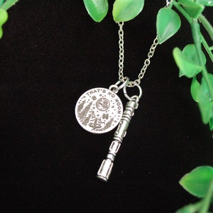 May include: Silver necklace featuring a round pendant inscribed with the words "That's no moon" and a silver charm resembling a lightsaber.