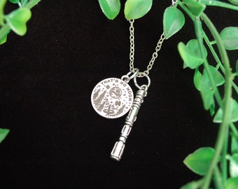May include: Silver necklace featuring a round pendant inscribed with the words "That's no moon" and a silver charm resembling a lightsaber.