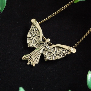 May include: A gold-toned necklace with a detailed steampunk-style angel pendant featuring intricate gears and wings.