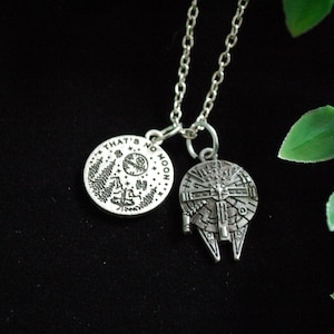 May include: A silver necklace with two charms. One charm is a round disc with the text "That's no moon" and a depiction of the Death Star. The other charm is a silver Millennium Falcon.
