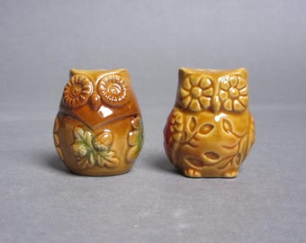 May include: A pair of ceramic owl salt and pepper shakers with brown, green, and white autumnal designs.