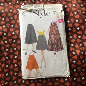 May include: Vintage Style 2229 sewing pattern featuring illustrations of skirts. The pattern includes sizes 3/6 and measurements for waist 24 inches and hip 34 inches. The pattern is on a patterned fabric background.