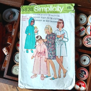 May include: Vintage Simplicity sewing pattern, size 4, for a child's coat. The pattern features illustrations of children wearing different coat styles. The pattern's text includes "5838 Simplicity" and "WE REGRET THAT PAPER PATTERNS CANNOT BE EXCHANGED."
