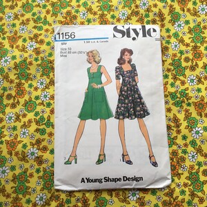 May include: A vintage sewing pattern titled "Style 1156" featuring illustrations of two dresses. The pattern includes size 10, with a bust measurement of 32 1/2 inches. The background is a yellow floral fabric.
