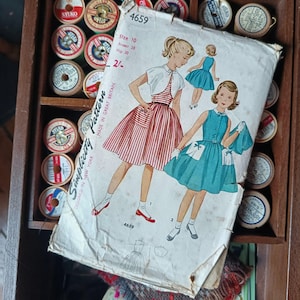 May include: Vintage Simplicity sewing pattern, size 10, featuring illustrations of dresses. The pattern is marked with the number 4659 and includes measurements for a 28-inch bust and 30-inch hips. The pattern is surrounded by spools of thread.