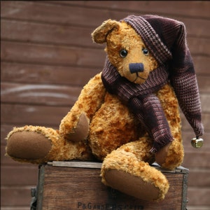 May include: A brown teddy bear wearing a brown and white plaid hat and scarf. The bear is sitting on a wooden box.