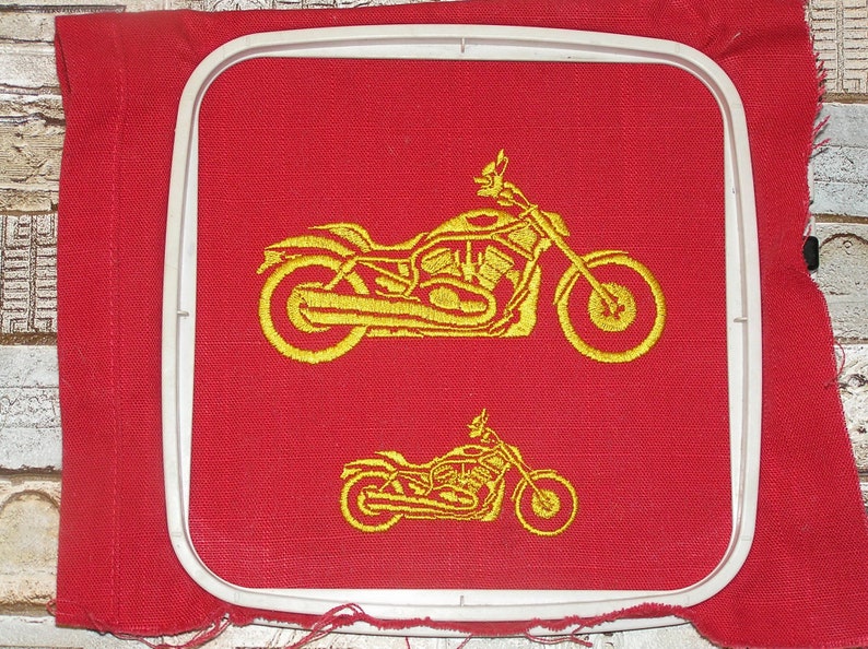 May include: A red fabric embroidery hoop with a gold embroidered image of a motorcycle. The motorcycle is shown twice, once large and once small.
