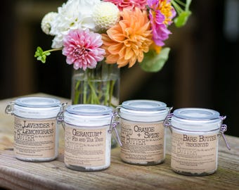 May include: Four glass jars with metal wire-bail lids containing body butter, each with a tan label reading Lavender + Lemongrass, Geranium + Fir and Tea Tree, Orange + Spice, and Bare Butter Unscented, with a net weight of 4.0 oz.