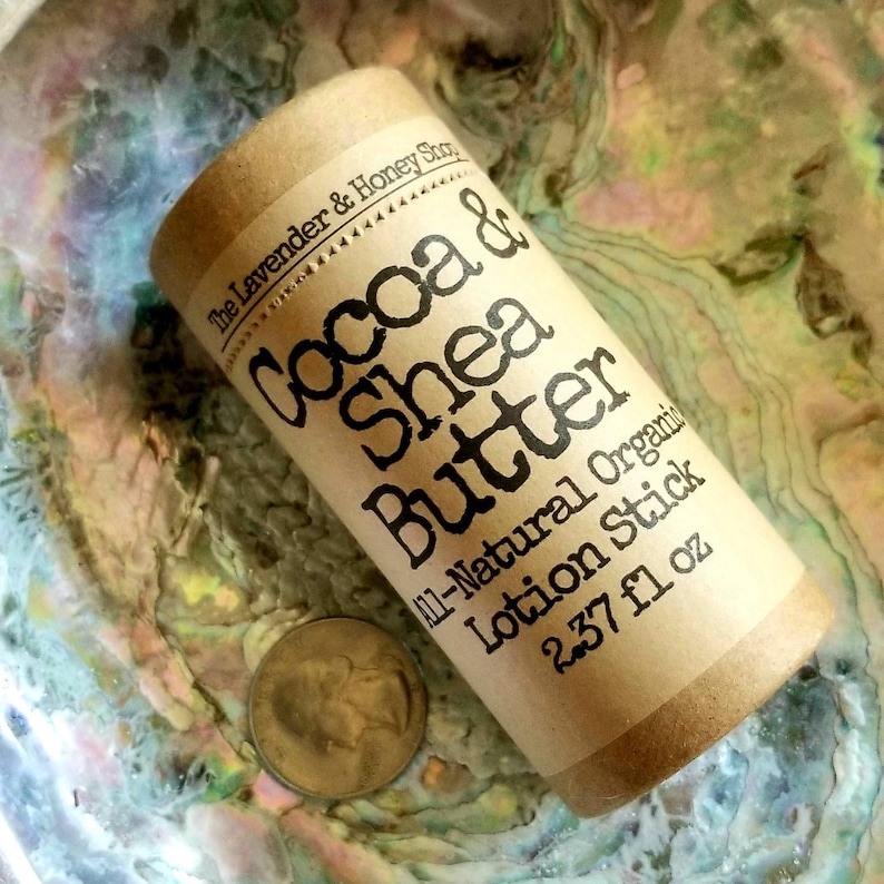 May include: A brown cardboard tube with a white label that reads "The Lavender & Honey Shop, Cocoa & Shea Butter All-Natural Organic Lotion Stick 2.37 fl oz".