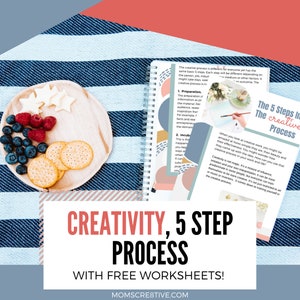 May include: A blue and white striped blanket with a wooden plate of crackers and berries. A notebook with the text "The 5 Steps In The Creative Process" is open on the blanket. The text "CREATIVITY, 5 STEP PROCESS WITH FREE WORKSHEETS! MOMSCRE8TIVE.COM" is on a pink and red rectangle.