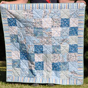 May include: A blue and white patchwork quilt with a striped border. The quilt is made of various fabrics with a nautical theme.