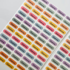 May include: A sheet of colorful oval stickers with the name "Gianna" printed on each sticker. The stickers are in various colors, including purple, green, yellow, orange, and blue.