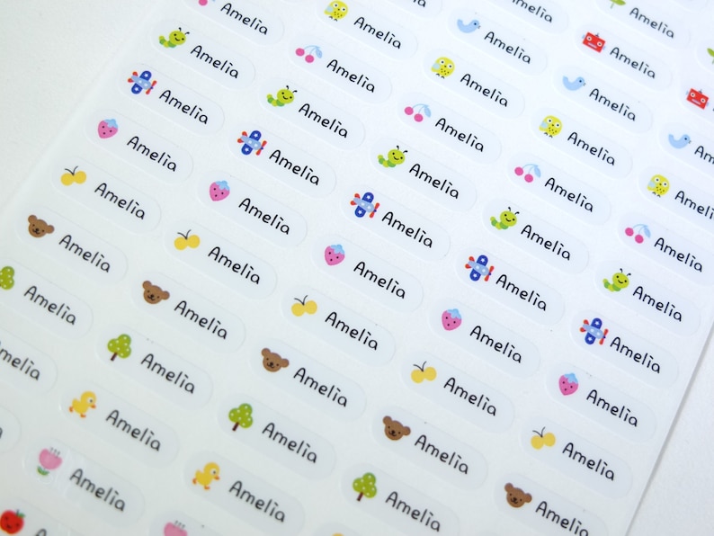 May include: A sheet of white labels with the name Amelia printed on each label. The labels have various colorful illustrations, including butterflies, airplanes, cherries, caterpillars, and bears.