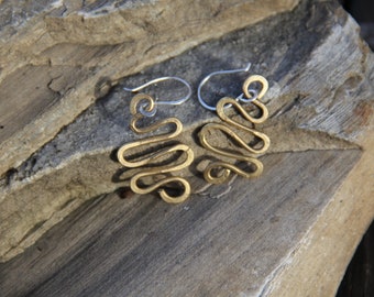 May include: A pair of gold-toned earrings with a wavy, abstract design. The earrings are made of metal and have a simple, modern style.