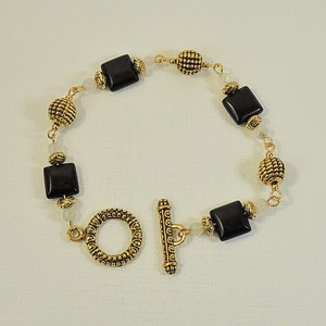 Bracelet in black stones and rose quartz. Golden stainless steel beads.
