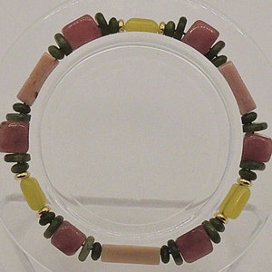 May include: A bracelet made of pink, green, and yellow beads. The beads are arranged in a repeating pattern.