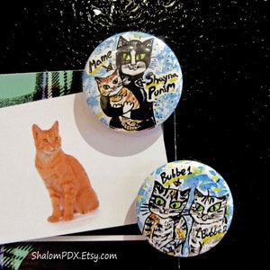 May include: Three round pinback buttons with colorful illustrations of cats. The first button features a black cat holding a smaller orange tabby cat with the text "Mame & Shayna Punim". The second button features two tabby cats with the text "Bubbe 1 & Bubbe 2".