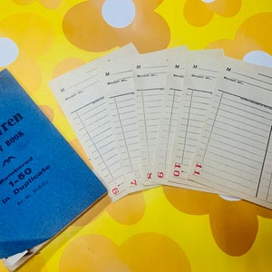 Puede incluir: Un libro azul con el título "The Blue Wren Docket Book" y el texto "Numbered 1-50 in Duplicate" en la portada. Hay seis formularios en blanco con la letra "M" y la palabra "Bought of" impresa en ellos. Los formularios están numerados del 6 al 11.