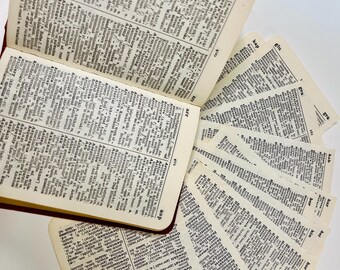 May include: An open dictionary with pages fanned out, showing definitions for words starting with "A" and "G". The pages are yellowed with age, and the book has a red leather cover.