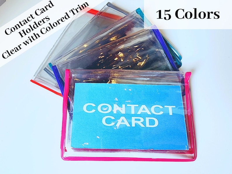 May include: A stack of clear plastic contact card holders with colored trim. The top holder has a pink trim and a blue card inside that says "CONTACT CARD". The text "15 Colors" is visible in the top right corner of the image.