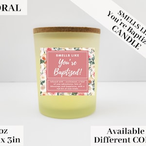 May include: A 3 ounce floral candle with a pink and white floral design label. The label reads "Smells Like You're Baptized!" and "Infused with excitement, a hint of new adventures, lots of blessings and happiness, with a tad bit of new trials."
