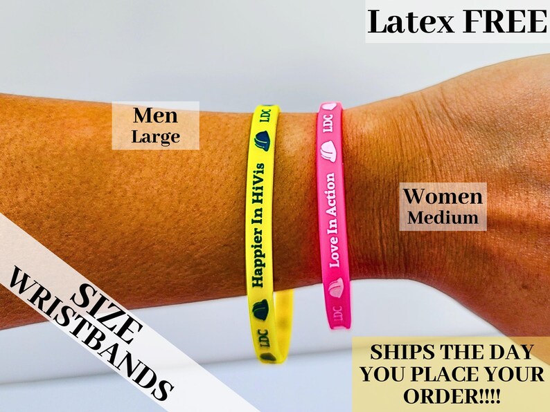 May include: Two silicone wristbands, one yellow with the text "Happier In HiVis" and the other pink with the text "Love In Action". The wristbands are on a person's arm. The text "Latex FREE" is at the top of the image. The text "SIZE WRISTBANDS" is at the bottom left of the image. The text "Men Large" is at the top left of the image. The text "Women Medium" is at the top right of the image. The text "SHIPS THE DAY YOU PLACE YOUR ORDER!!!!" is at the bottom right of the image.