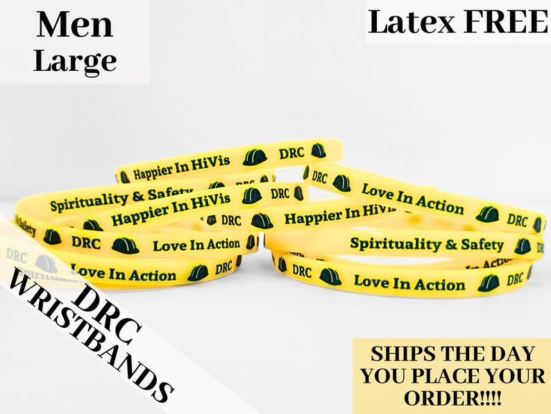 May include: A close-up of yellow silicone wristbands with black text and a green construction helmet graphic. The text on the wristbands reads "DRC", "Happier In HiVis", "Spirituality & Safety", and "Love In Action".