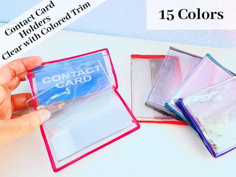 May include: Clear plastic contact card holders with colored trim. The holders are stacked and show 15 different colors. The text "CONTACT CARD" is visible on one of the holders.