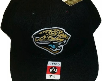 May include: Black fitted baseball cap with a Jacksonville Jaguars logo embroidered on the front. The logo features a teal, gold, and white jaguar head. The cap has a fitted size of 7 1/2.