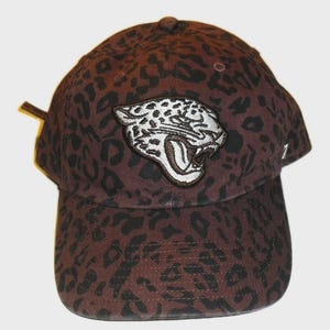 May include: A brown baseball cap with a leopard print pattern and a white and black embroidered jaguar patch. The cap has a curved brim and an adjustable strap.