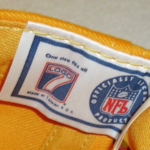 May include: A white tag with blue trim and text that reads "One size fits all" and "Logo 7" with a blue and white logo of the number 7. The tag also reads "Made in Taiwan, R.O.C." and "Officially Licensed NFL Product" with a blue and red NFL logo.