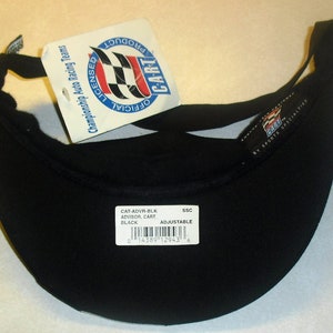 Pode incluir: Visor preto ajust&aacute;vel com o texto "CART" e "OFFICIAL LICENSED Championship Auto Racing Teams" na etiqueta. O visor &eacute; etiquetado "CAT-ADVR-BLK ADVISOR, CART BLACK" e tem um c&oacute;digo de barras.