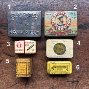 May include: Collection of vintage metal tins, including a rectangular tin with "PINS" text, a "Player's Navy Cut Cigarettes" tin, and a "Waverley Pen" tin. Other tins include "Sample for Study" and "Dr. Bengue's Balsam".