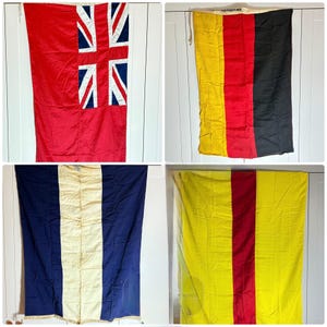 May include: Four vintage flags are shown. The top left flag is red with a Union Jack design. The top right flag is yellow, red, and black. The bottom left flag is blue and white. The bottom right flag is yellow and red. All flags are rectangular.