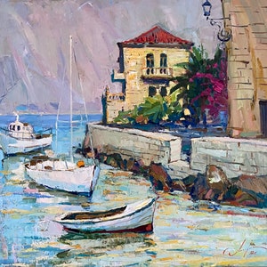 Puede incluir: Una pintura de una escena de puerto con tres barcos atracados cerca de un muro de piedra. Los barcos son blancos y el agua es azul. Un edificio amarillo con un techo rojo est&aacute; en el fondo.