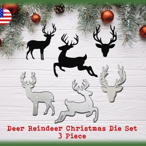 May include: A set of three metal Christmas die cuts featuring reindeer. The die cuts are silver and black and include a reindeer head, a standing reindeer, and a reindeer in a running pose. The text "Deer Reindeer Christmas Die Set 3 Piece" is printed below the die cuts.