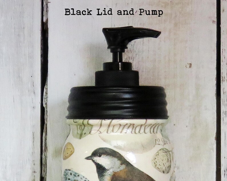 May include: A glass jar with a black lid and pump. The jar has a floral design with a bird on it. The text "Almada" is visible on the jar.