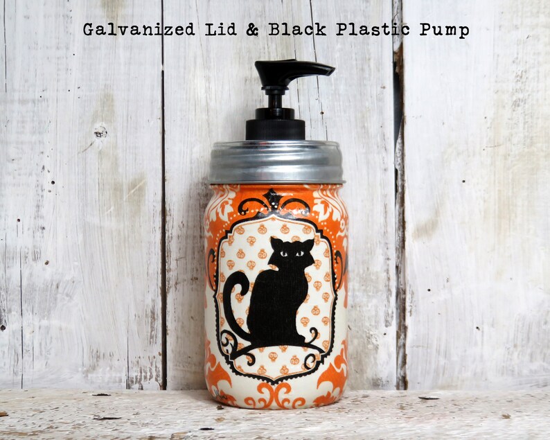 May include: Orange and white Halloween themed glass jar with a black cat design and a black plastic pump dispenser. The jar has a galvanized metal lid.