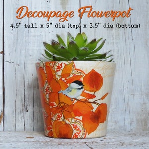 May include: A decoupage flowerpot with a bird and orange leaves design. The pot is 4.5 inches tall, 5 inches in diameter at the top, and 3.5 inches in diameter at the bottom.