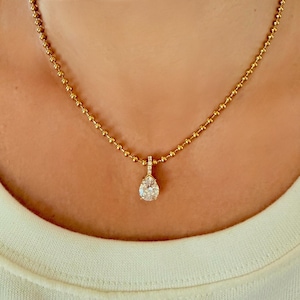 Close-up of pear shaped CZ pendant resting on collarbone on 18K PVD gold 3mm ball chain showing warm yellow gold tone and teardrop cubic zirconia detail