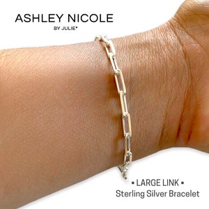 May include: A silver chain bracelet with large links. The bracelet is on a person's wrist. The text "LARGE LINK" and "Sterling Silver Bracelet" is below the bracelet.