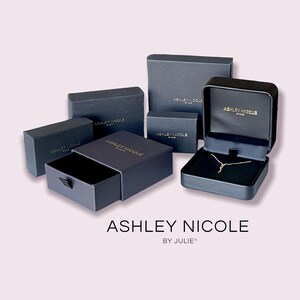 May include: Multiple black boxes with gold lettering that reads "Ashley Nicole by Julie" and a gold necklace inside one of the boxes.