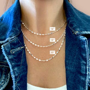 May include: Three silver chain necklaces layered on a model's neck. The chains are 16 inches, 18 inches, and 20 inches long.