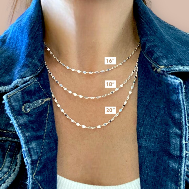 May include: Three silver chain necklaces layered on a model's neck. The chains are 16 inches, 18 inches, and 20 inches long.