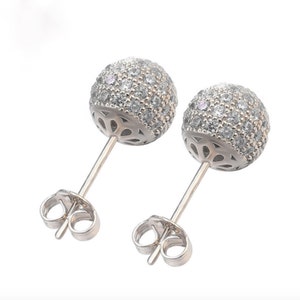 Close up of a pair of silver stud earrings with a round, clear crystal design. The earrings have a post and butterfly back.
